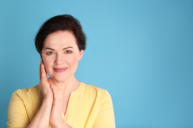 Portrait of charming mature woman with healthy beautiful face skin and natural makeup on blue background, space for text