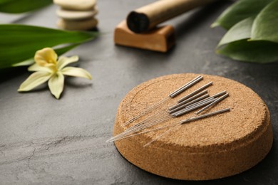 Photo of Cork coaster with acupuncture needles on black table. Space for text