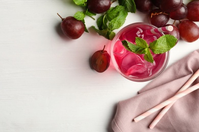 Photo of Delicious grape soda water, mint and berries on white table, flat lay with space for text. Refreshing drink