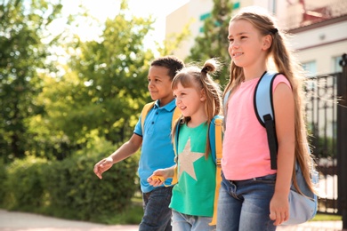 Photo of Cute little children with backpacks going to school