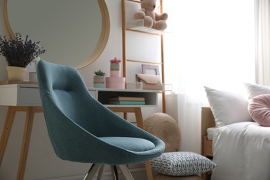 Photo of Comfortable blue chair in teenage girl's bedroom interior. Idea for design