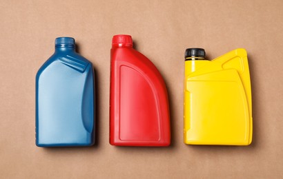 Photo of Motor oil in different canisters on light brown background, flat lay