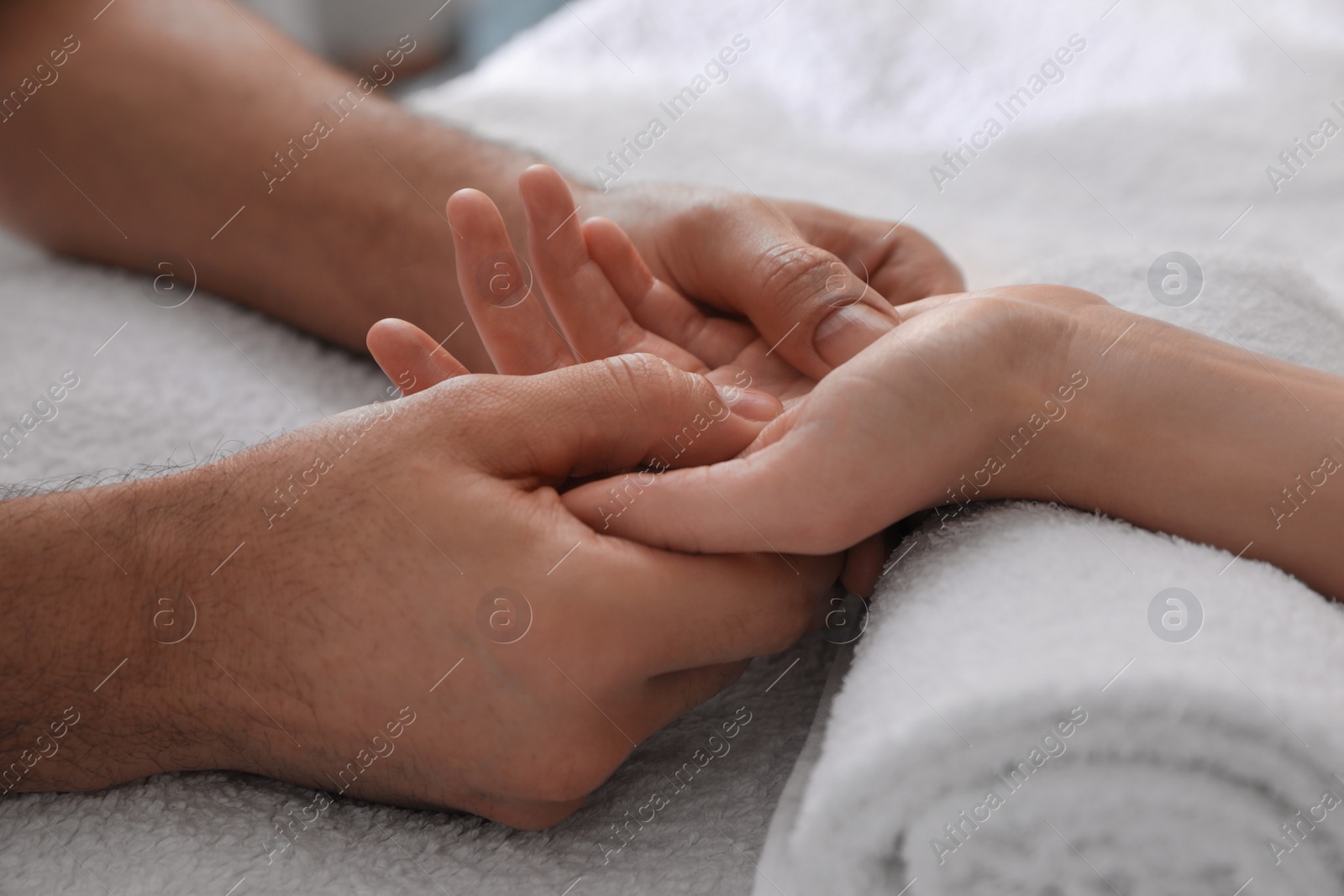 Photo of Woman receiving hand massage on soft towel, closeup