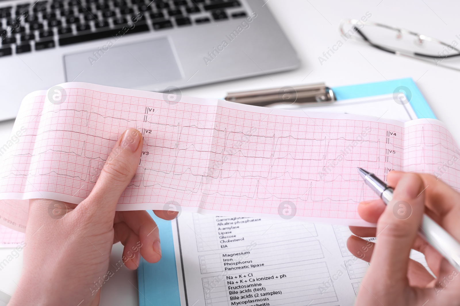 Photo of Doctor examining cardiogram at table in clinic, closeup