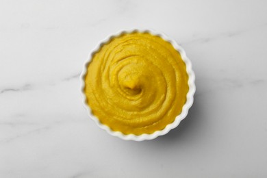 Photo of Tasty mustard sauce in bowl on white marble table, top view