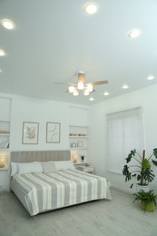 Photo of Comfortable furniture, ceiling fan, houseplants and accessories in stylish bedroom