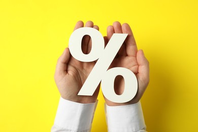 Photo of Man holding percent sign on yellow background, top view