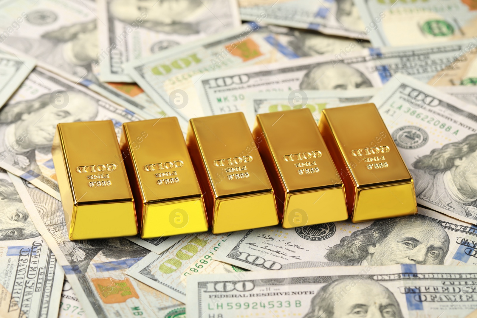 Photo of Many shiny gold bars on dollar banknotes