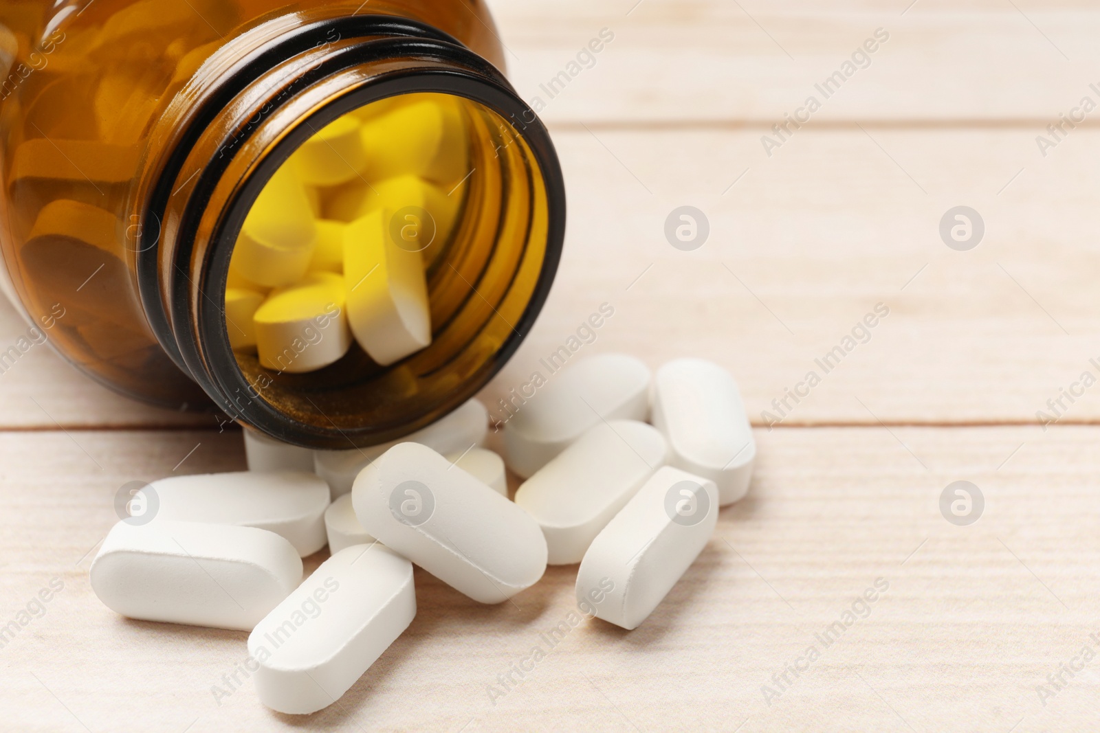 Photo of Bottle and vitamin pills on wooden table, closeup. Space for text