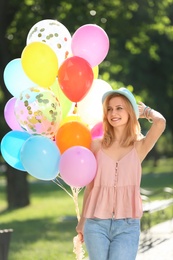 Photo of Young woman with colorful balloons outdoors on sunny day