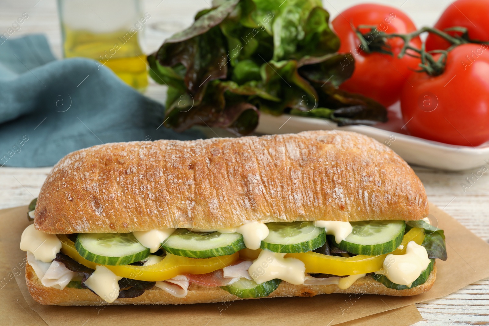 Photo of Delicious sandwich with vegetables, ham and mayonnaise on parchment paper, closeup