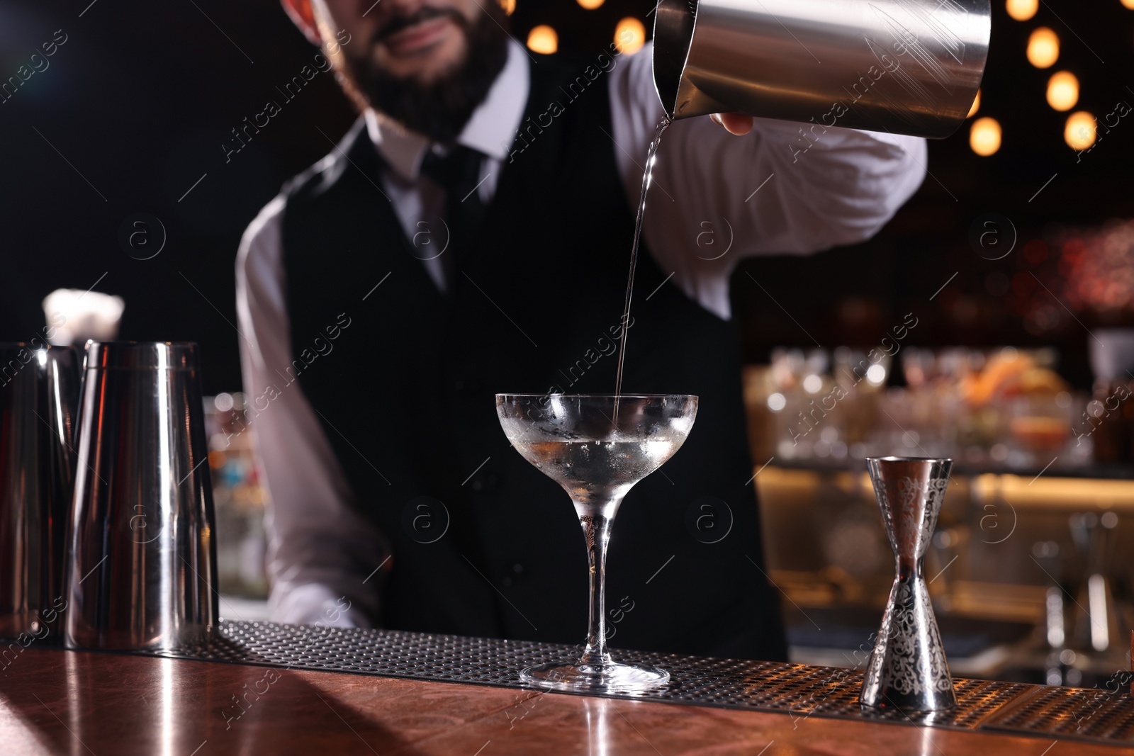 Photo of Bartender preparing fresh Martini cocktail at bar counter, closeup