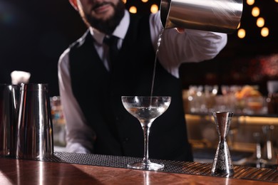 Bartender preparing fresh Martini cocktail at bar counter, closeup