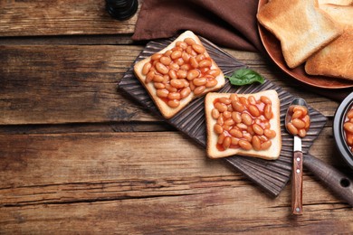 Toasts with delicious canned beans on wooden table, flat lay. Space for text