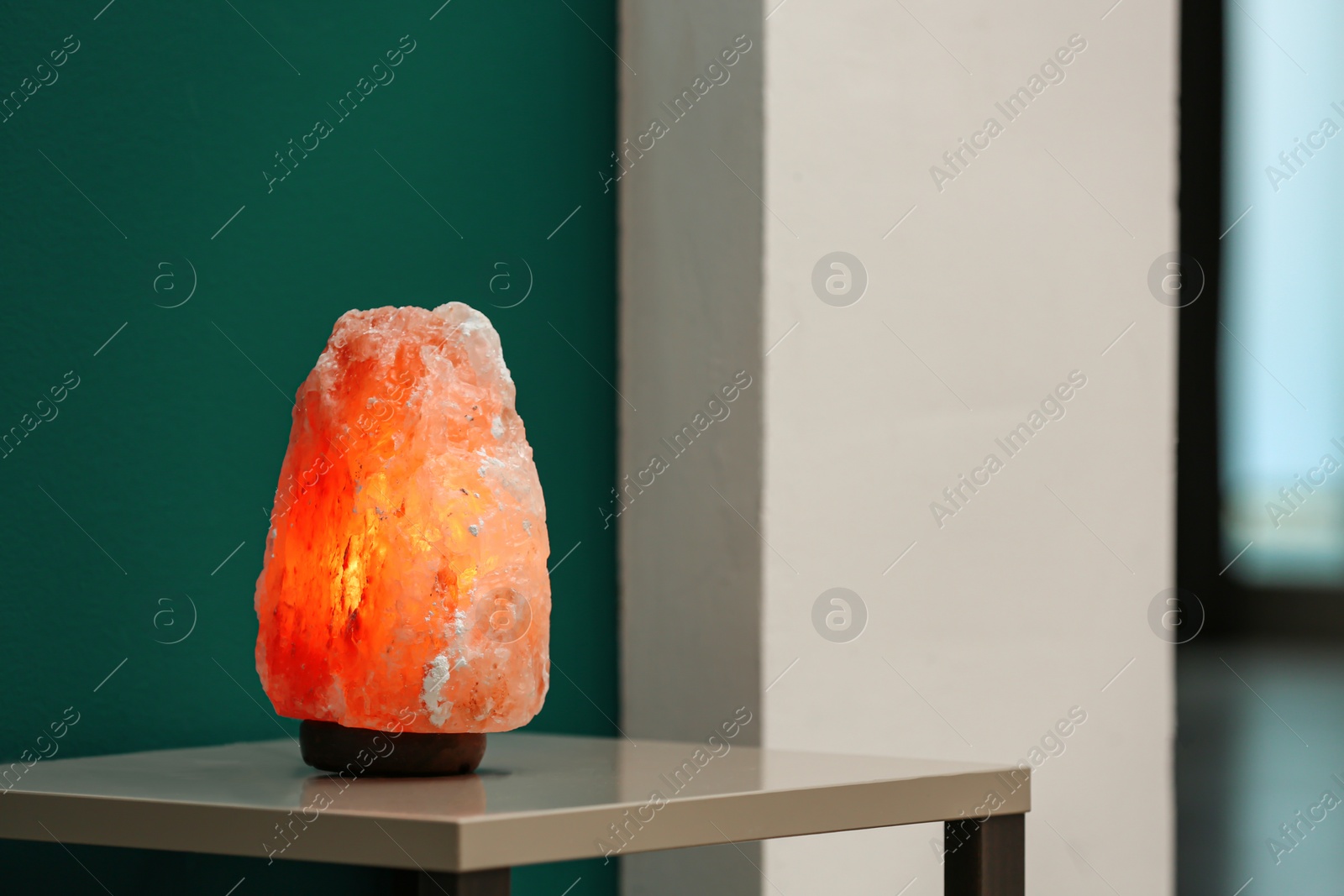 Photo of Himalayan salt lamp on table in room. Space for text