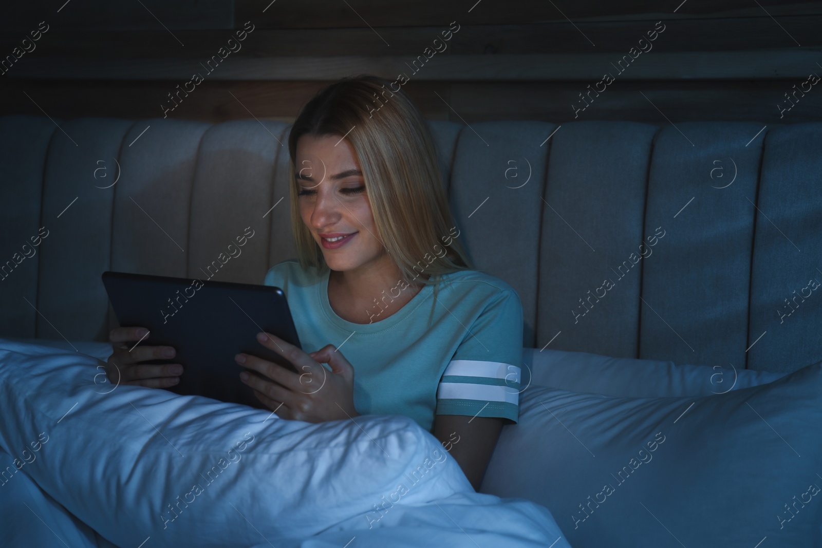 Photo of Young woman using tablet in bed at night. Sleeping disorder problem