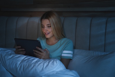 Photo of Young woman using tablet in bed at night. Sleeping disorder problem