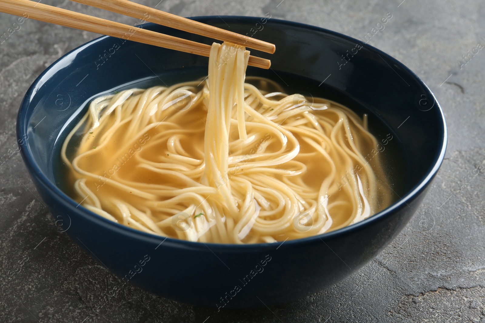Photo of Eating noodle dish with chopsticks on table, closeup