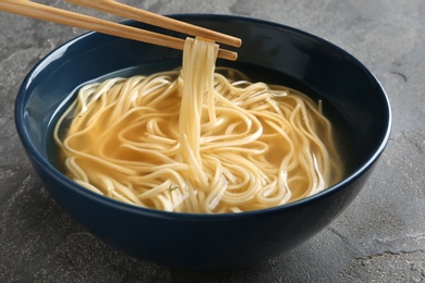Eating noodle dish with chopsticks on table, closeup