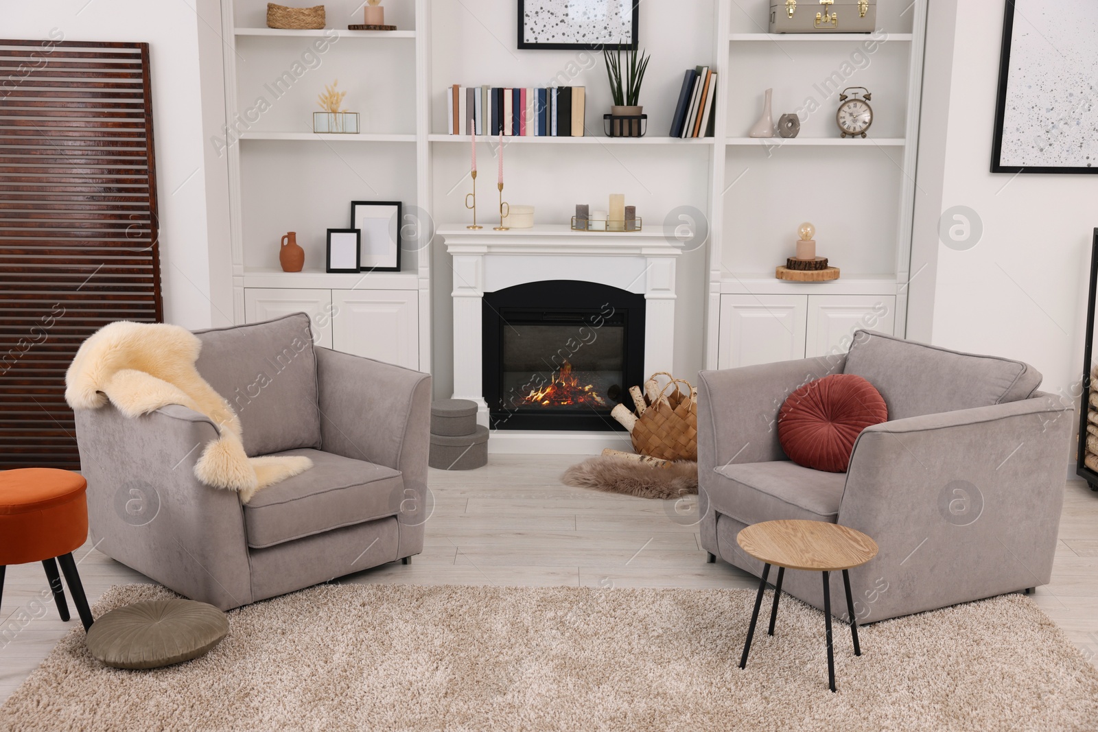 Photo of Comfortable armchairs, fireplace and shelves in living room. Interior design