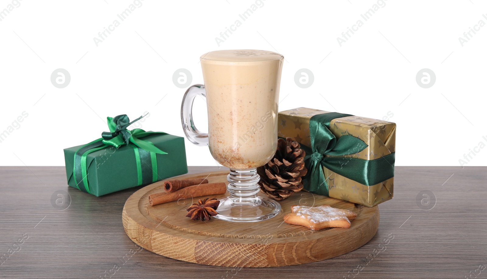 Photo of Delicious eggnog in glass, spices and gift boxes on wooden table against white background