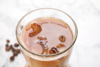 Photo of Refreshing iced coffee with milk in glass on white table, closeup