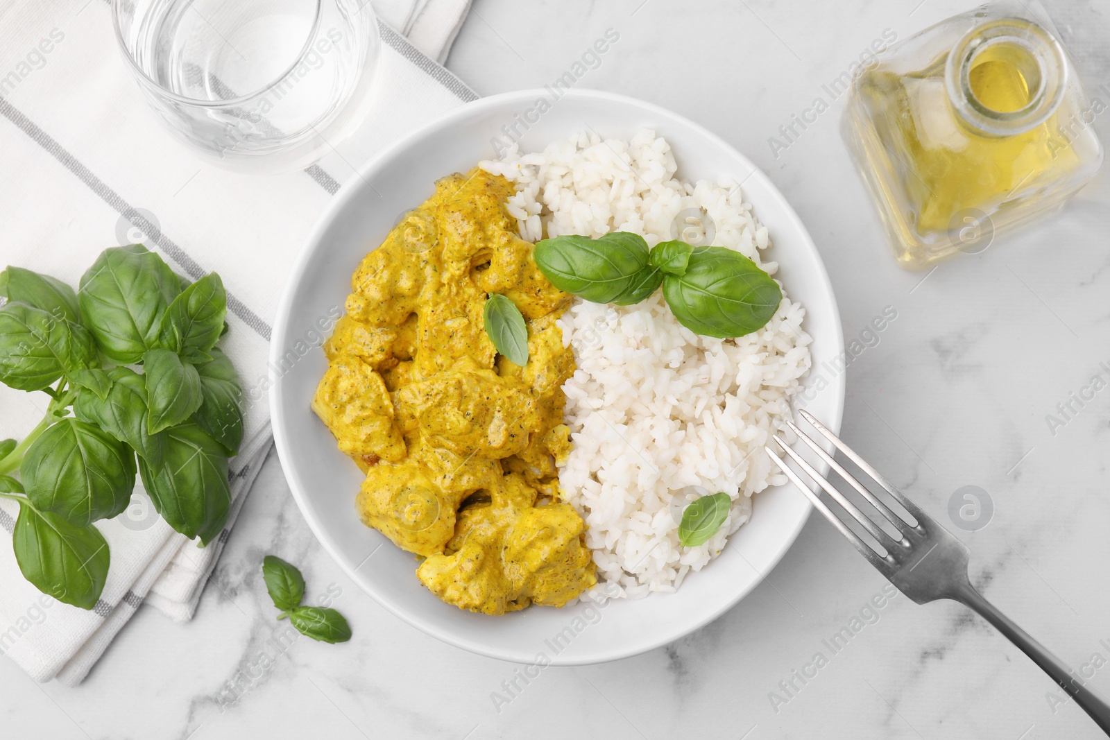 Photo of Delicious rice and chicken with curry sauce on white marble table, flat lay