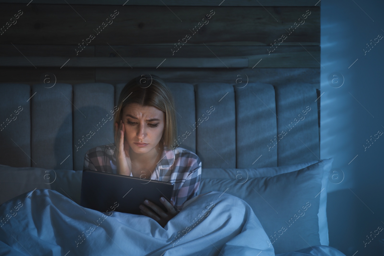 Photo of Young woman using tablet in bed at night. Sleeping disorder problem