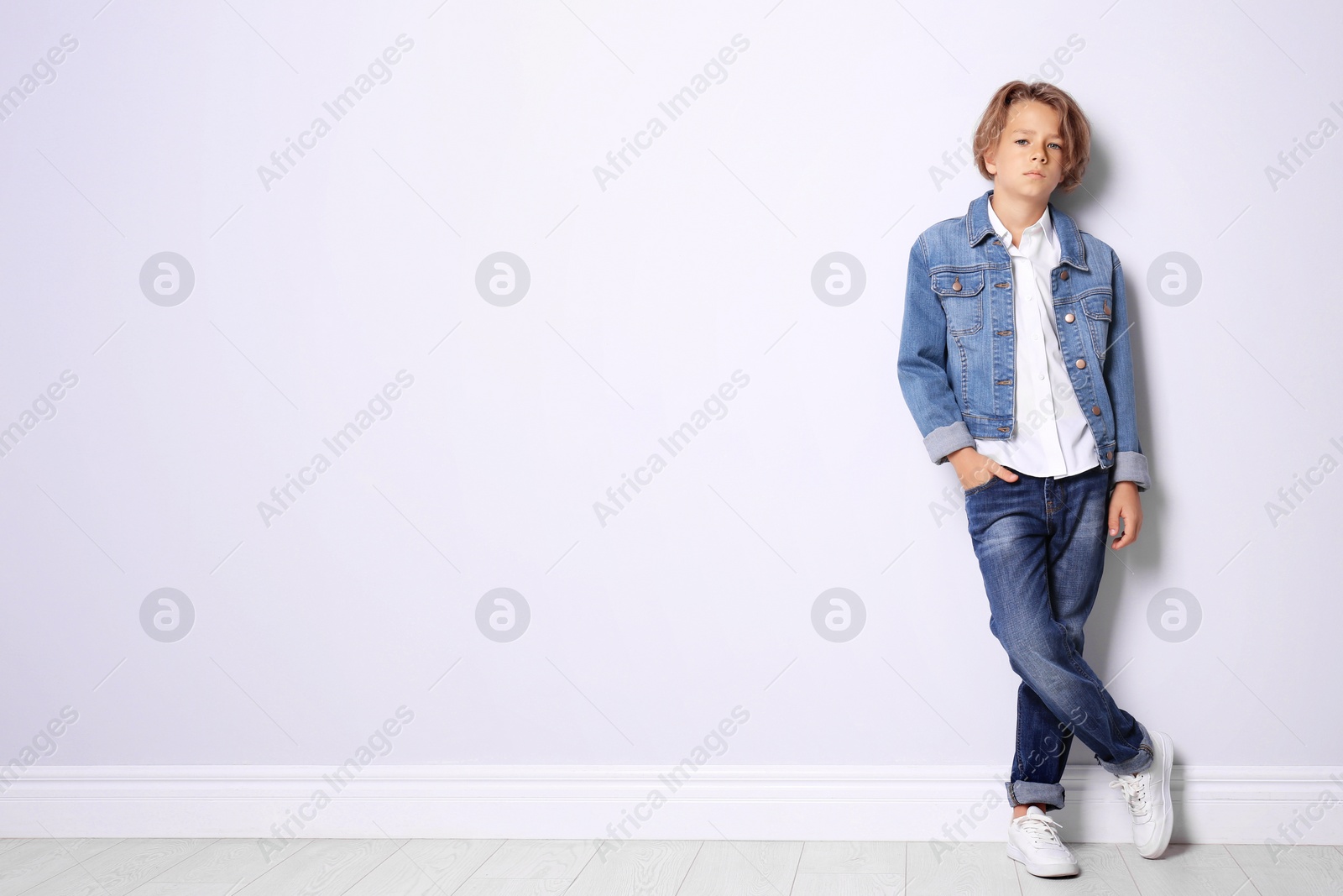 Photo of Cute little boy in casual outfit near white wall. Space for text