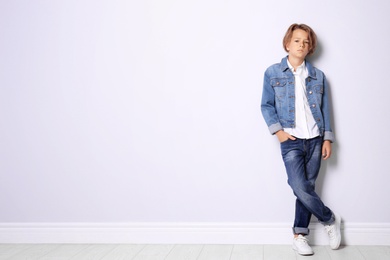 Photo of Cute little boy in casual outfit near white wall. Space for text