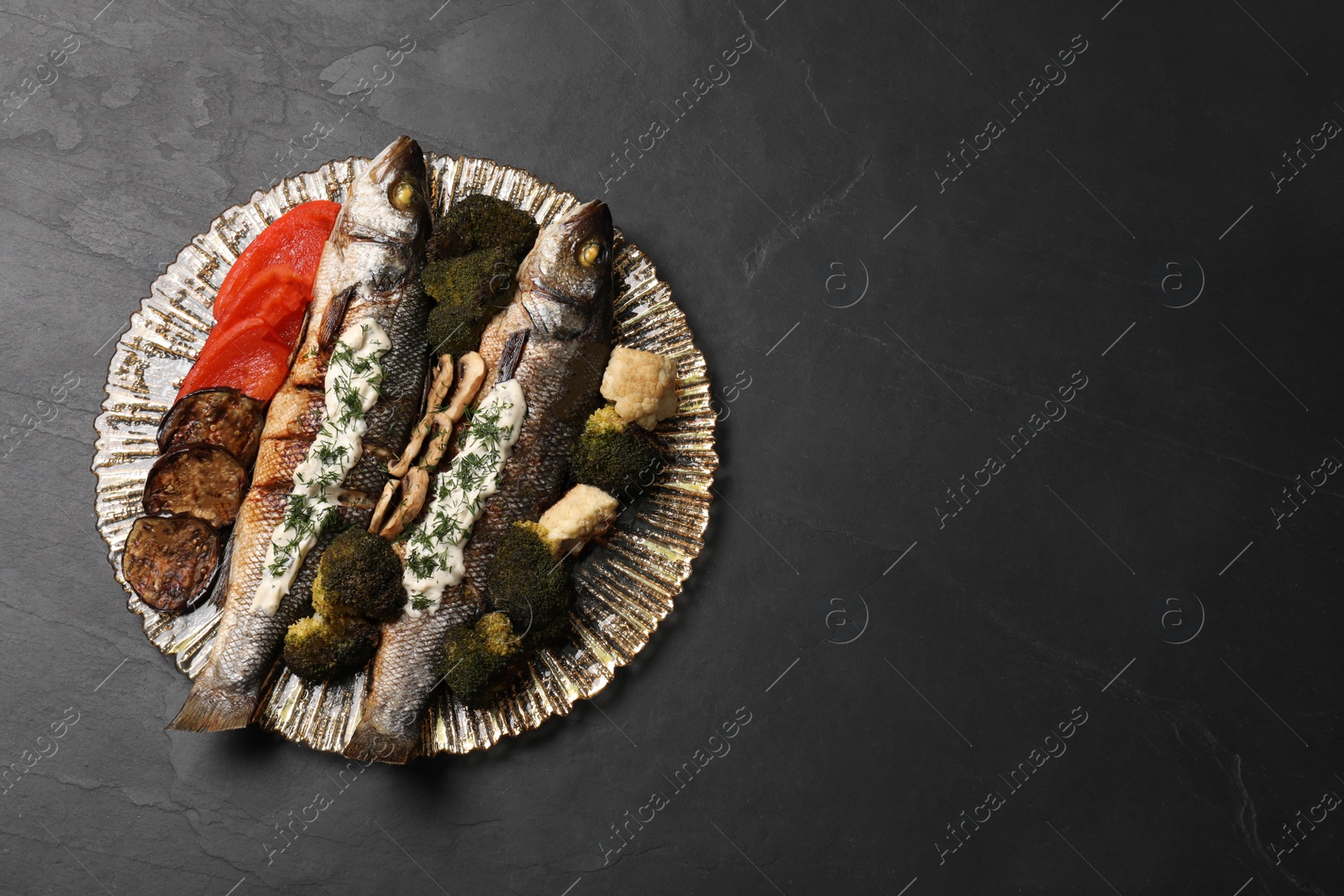 Photo of Plate with delicious sea bass fish and ingredients on dark grey table, top view. Space for text