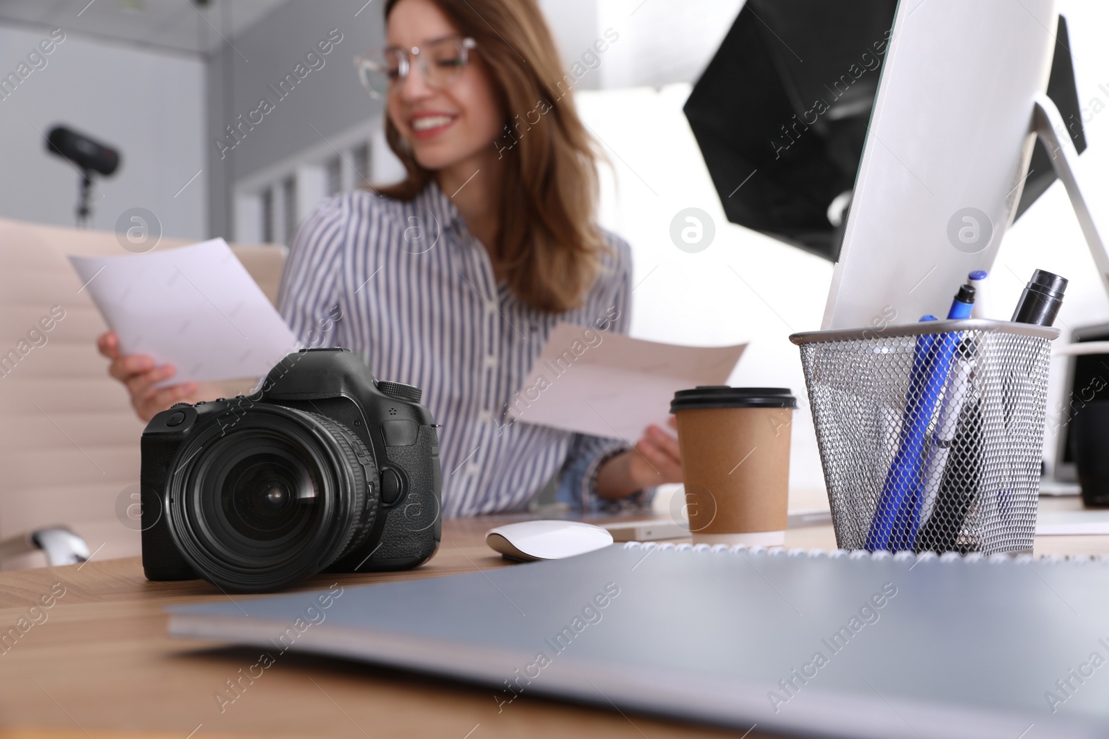 Photo of Professional photographer working at table in office, focus on camera