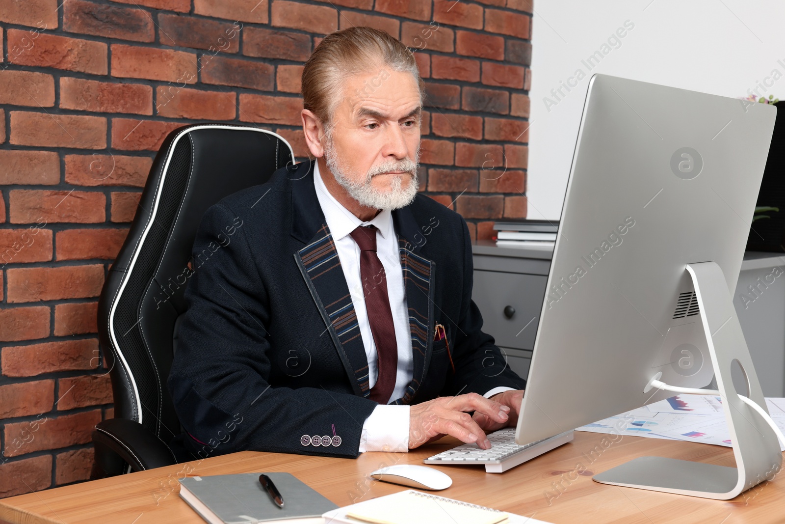Photo of Senior boss working at wooden table in modern office