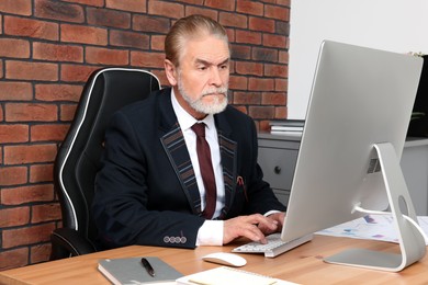 Senior boss working at wooden table in modern office