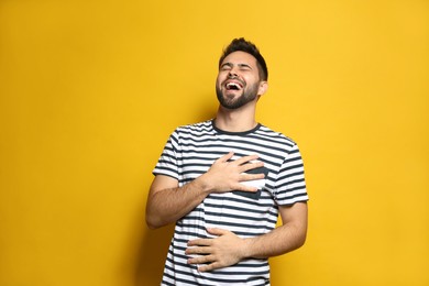 Photo of Young man laughing on yellow background. Funny joke