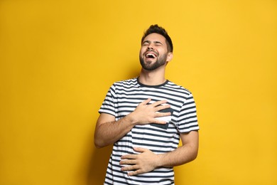 Young man laughing on yellow background. Funny joke