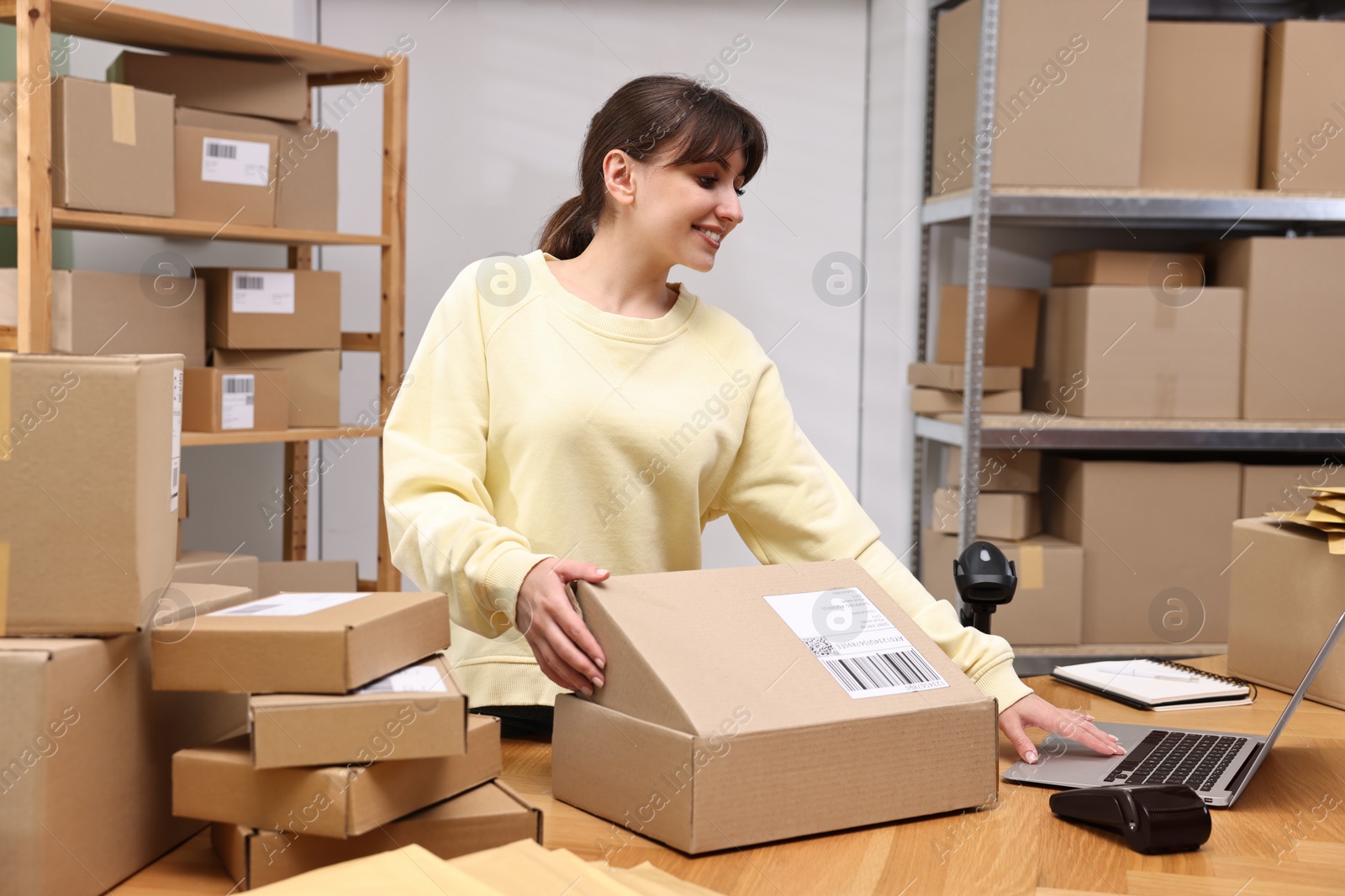 Photo of Post office worker packing parcel at wooden table indoors