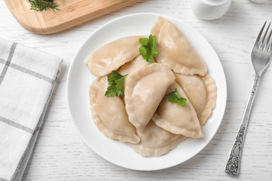 Photo of Tasty cooked dumplings served on white wooden table, flat lay