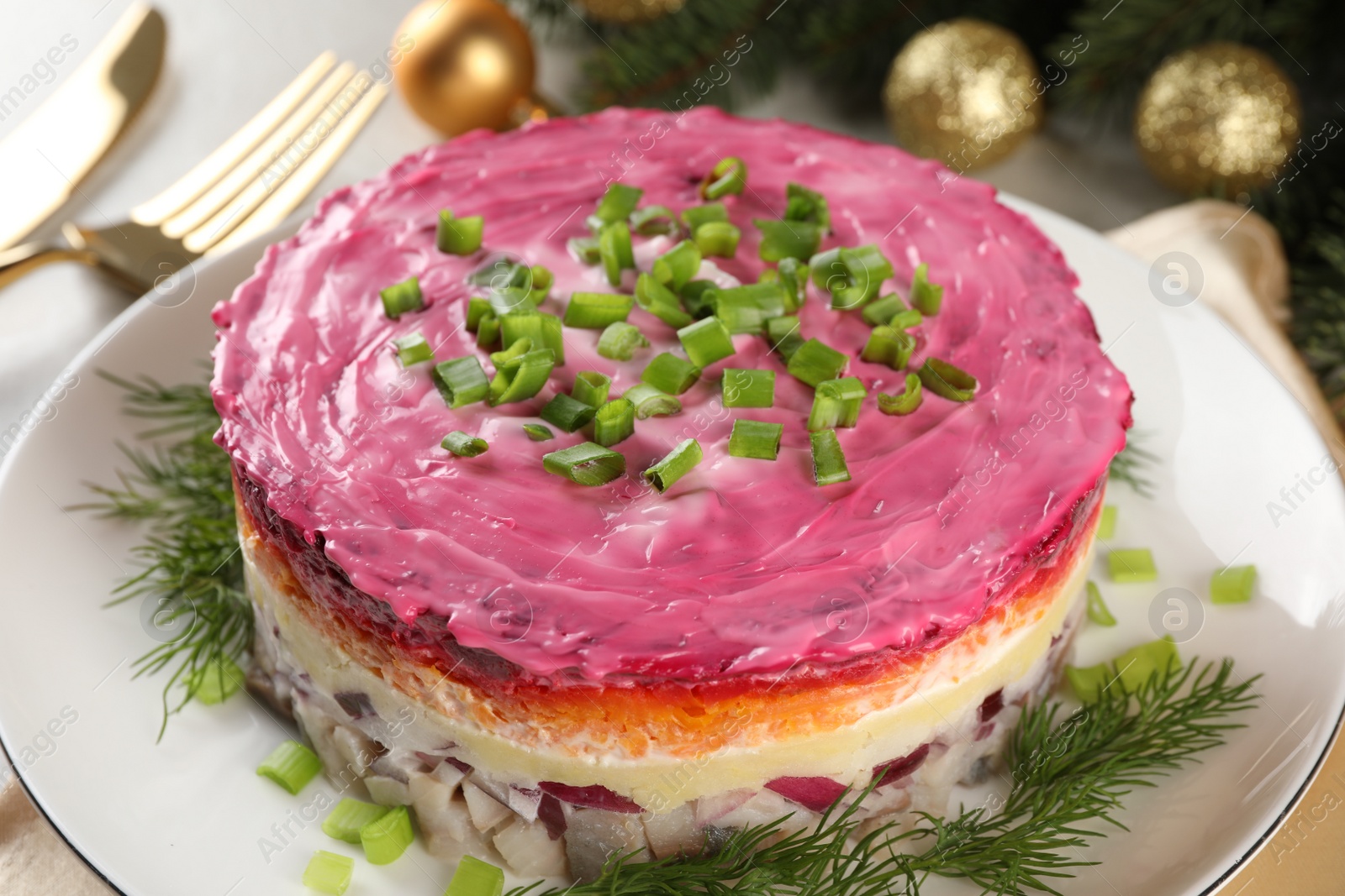 Photo of Herring under fur coat salad and Christmas decor on light grey table, closeup. Traditional Russian dish