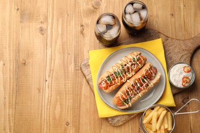 Delicious hot dogs with bacon, carrot and parsley served on wooden table, flat lay. Space for text