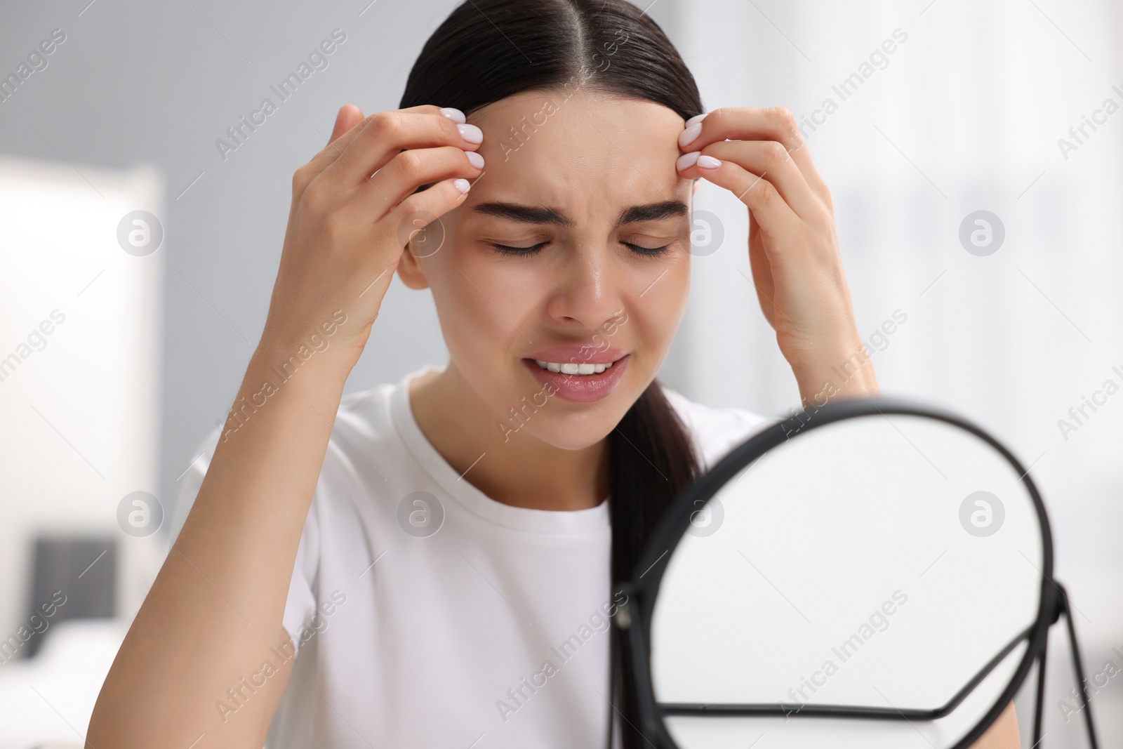 Photo of Woman with dry skin looking at mirror indoors