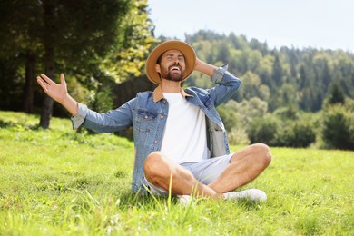Photo of Feeling freedom. Smiling man enjoying nature on green grass outdoors