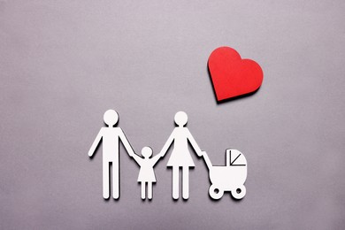 Photo of Figures of family under heart on lilac background, top view. Insurance concept
