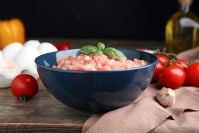 Photo of Raw chicken minced meat with basil and ingredients on wooden table, closeup