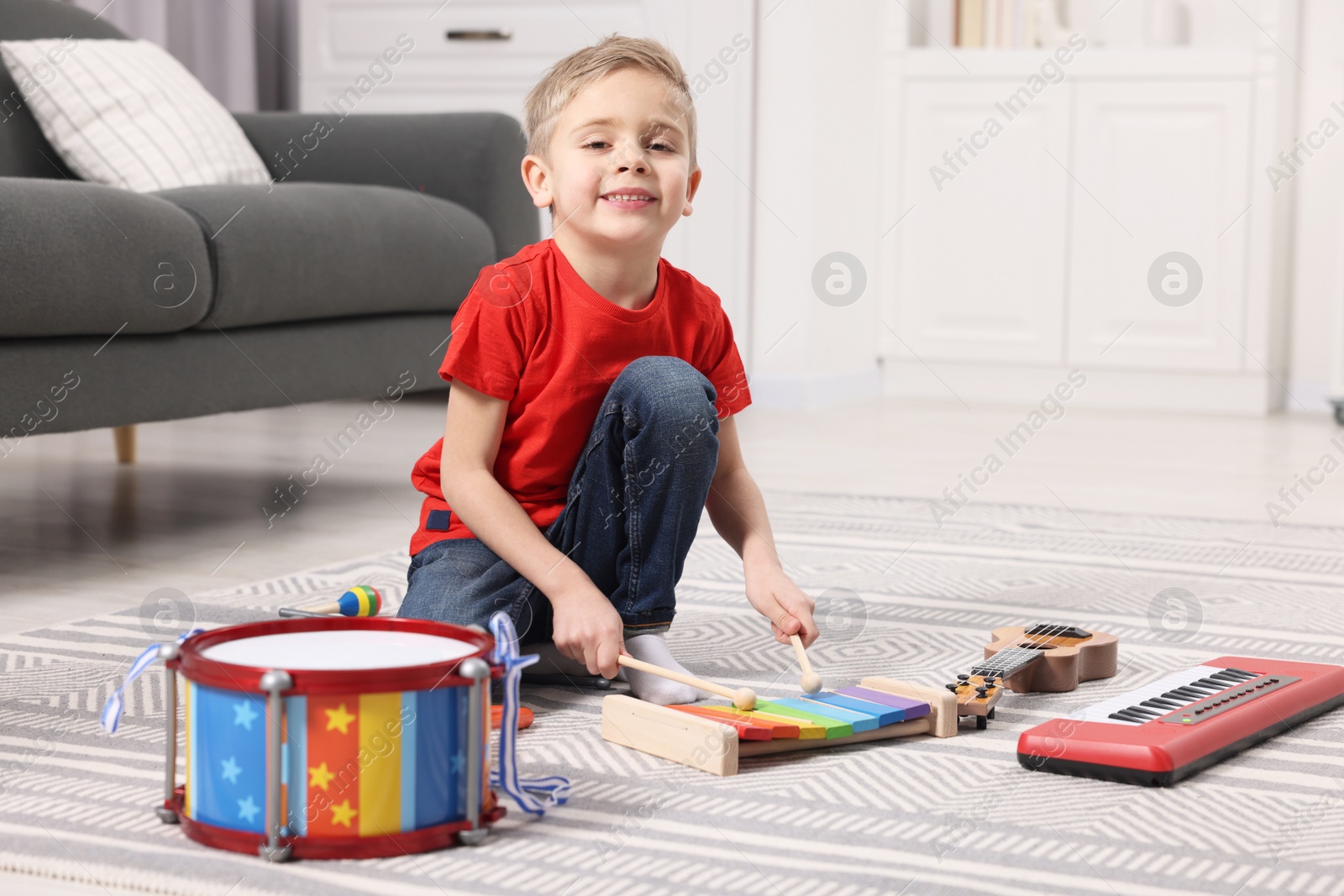 Photo of Little boy playing toy xylophone at home