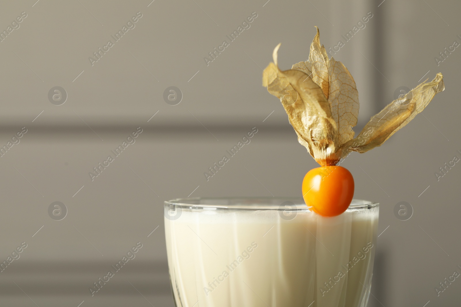 Photo of Refreshing cocktail decorated with physalis fruit on blurred background, closeup