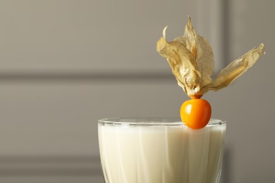 Photo of Refreshing cocktail decorated with physalis fruit on blurred background, closeup