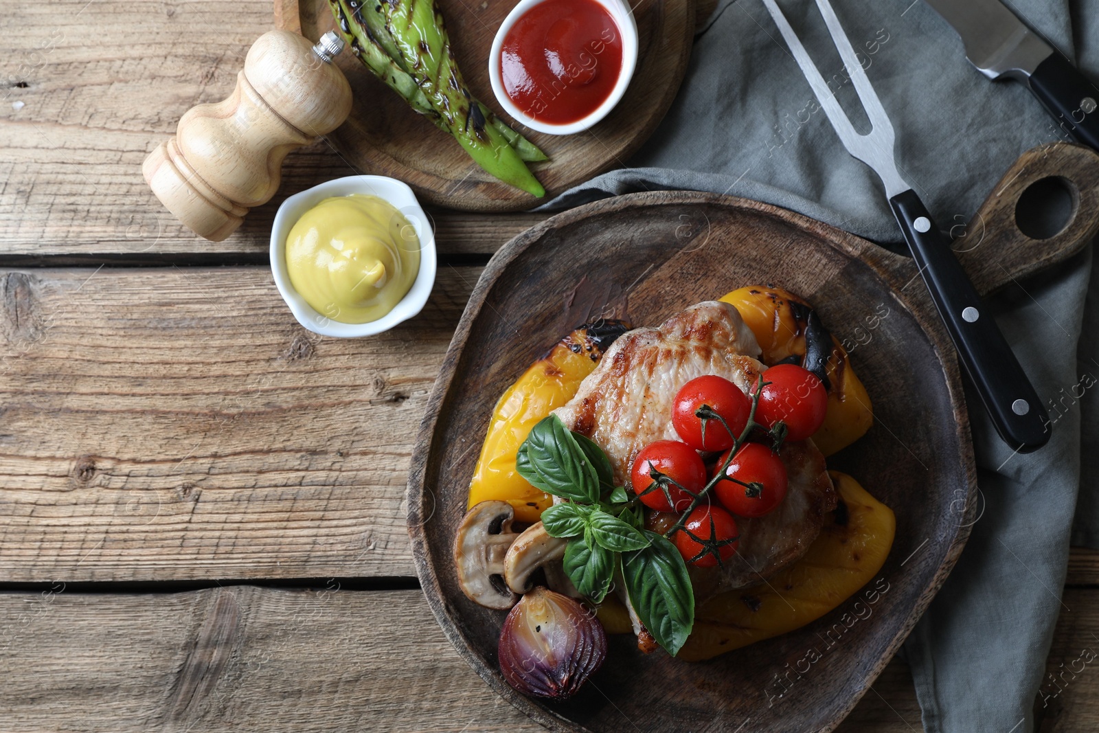 Photo of Delicious grilled meat and vegetables served with sauces on wooden table, flat lay. Space for text