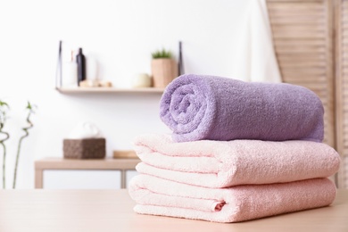 Photo of Stack of fresh towels on table in bathroom. Space for text