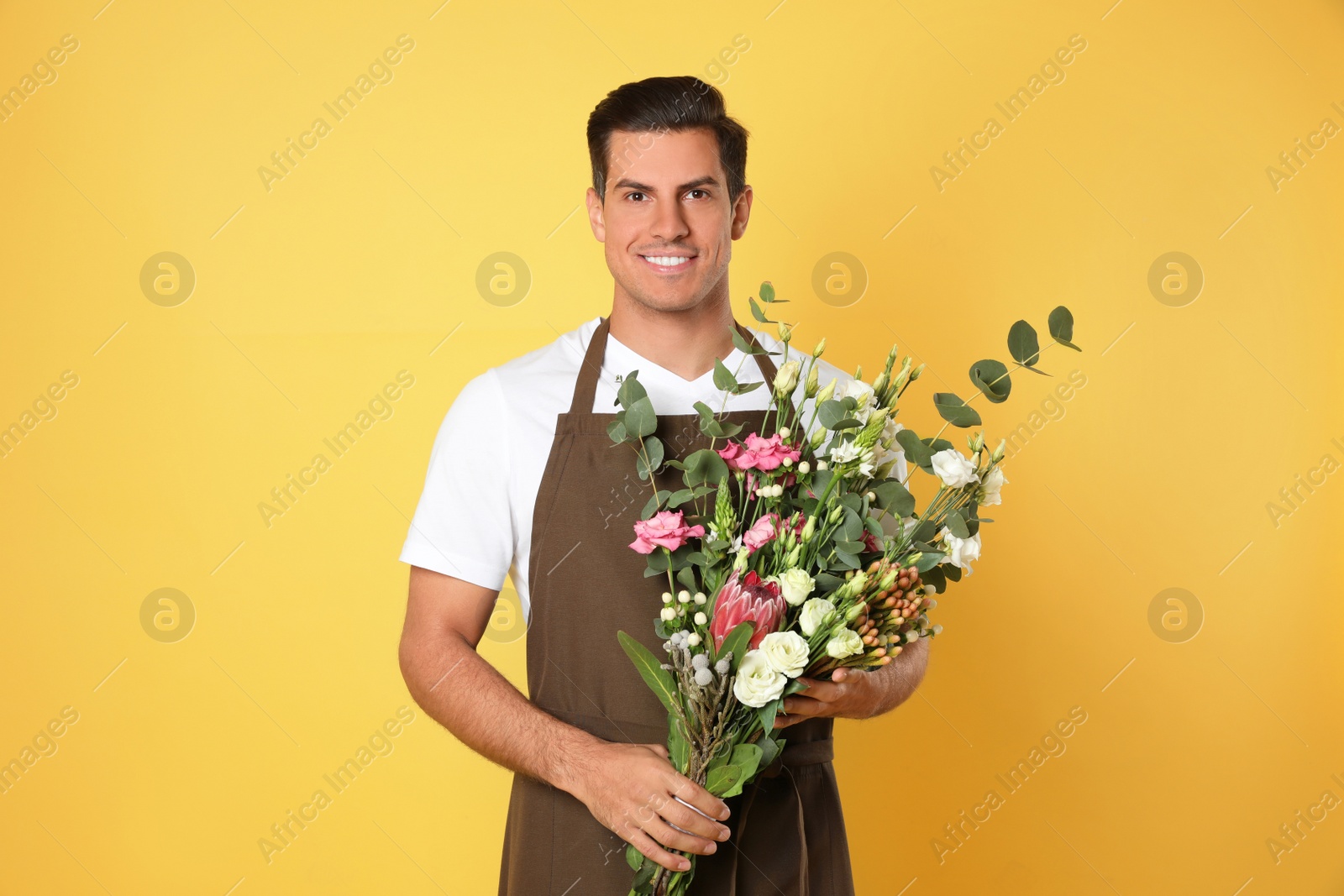 Photo of Florist with beautiful bouquet on yellow background
